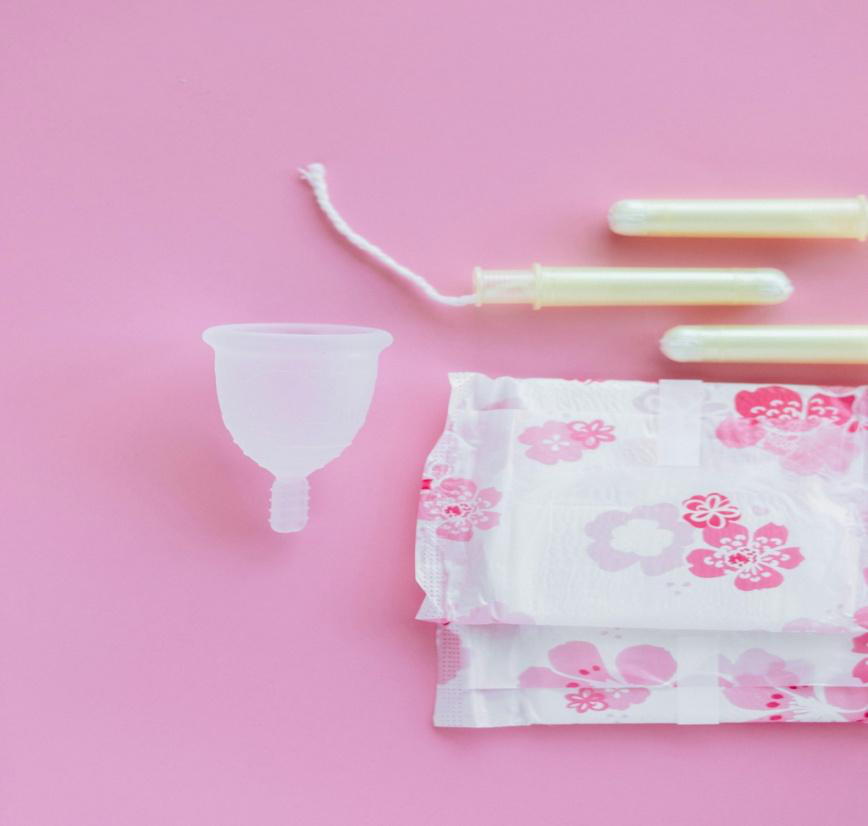 Tampons, a diva cup and a pad on a pink surface