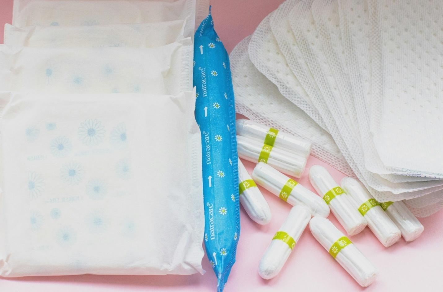 Tampons and pads scattered on a pink  surface