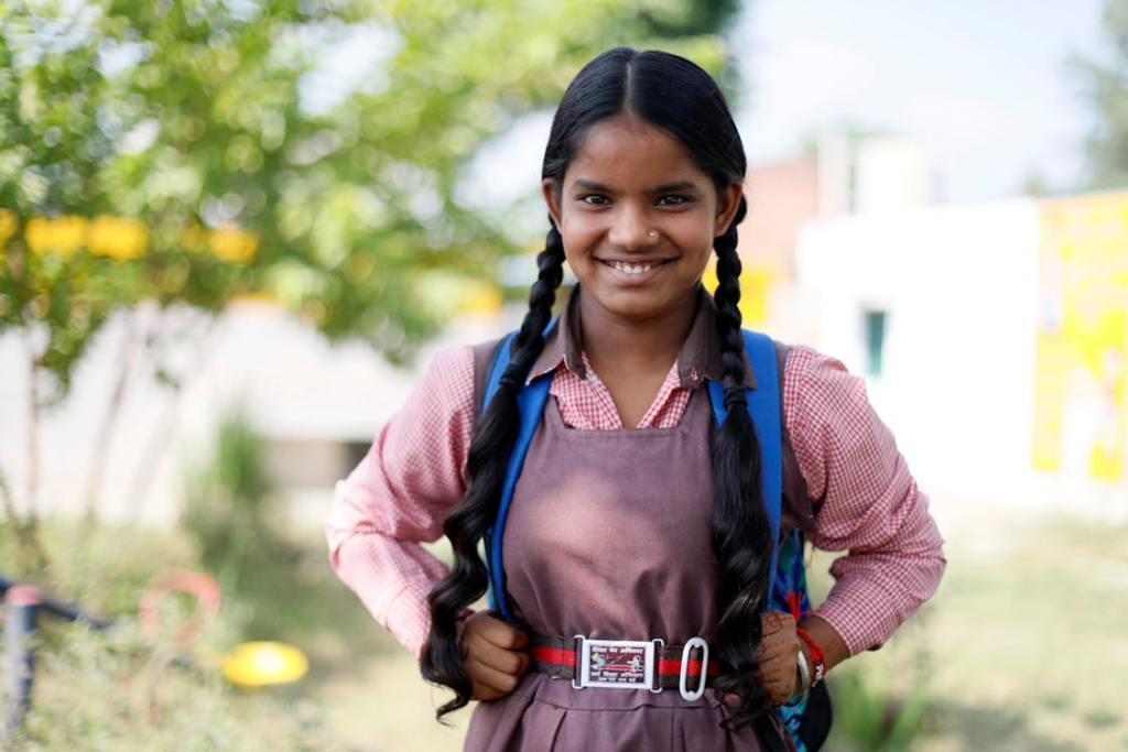 A smiling girl wearing her school uniform and backpack