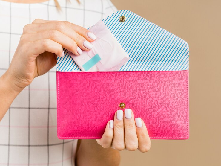 A woman holding a pad and a pink wallet.