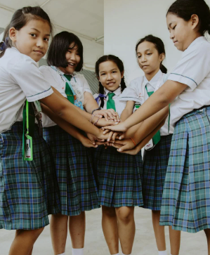 This image shows schoolgirls standing united with hands joined, reflecting confidence